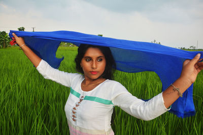 Portrait of woman standing on field against sky