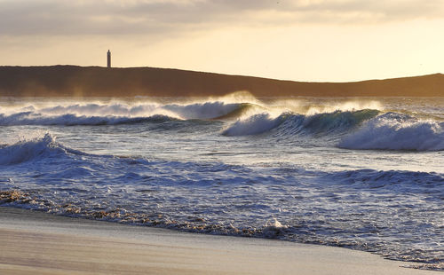 Waves rushing towards beach during sunset