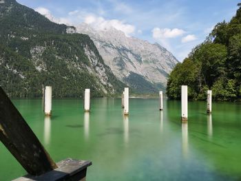 Wooden posts in lake against sky