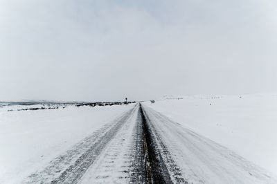 Snow covered road against sky