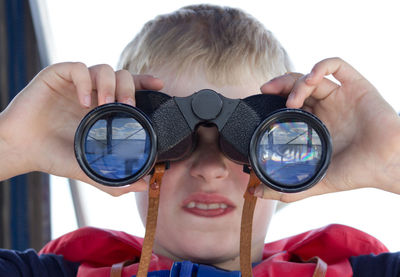 Close-up of boy looking through binoculars outdoors