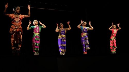 Group of people dancing against black background