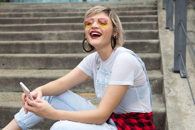 Young woman using mobile phone while sitting on staircase