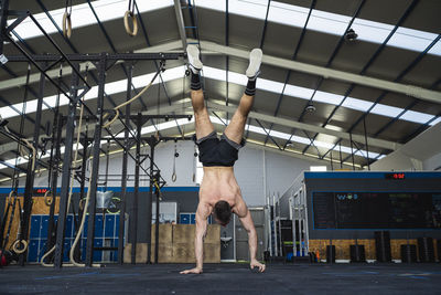 Young male athlete doing handstand in gym