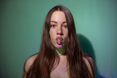 Portrait of beautiful young woman licking lollipop