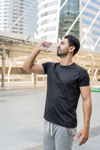 Full length of young man drinking glass in city