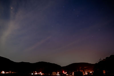 Silhouette town against sky at night