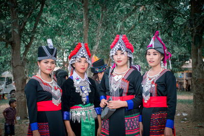 Portrait of smiling young women standing against trees