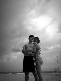 Low angle view of mother and son standing at beach against sky