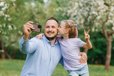 Close-up portrait of a happy family of two. smiling dad and six-year-old daughter take a selfie