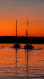 Silhouette sailboats in sea against romantic sky at sunset