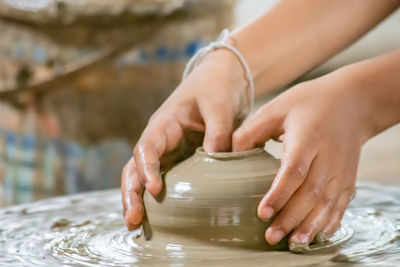 The fingers are shaped clay pot on a rotating tray.