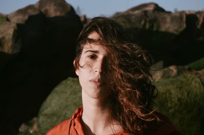 Portrait of young woman standing against rocks