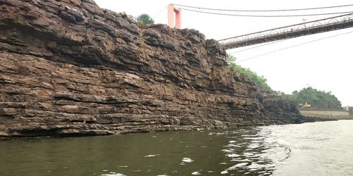 Rock formations by river against sky