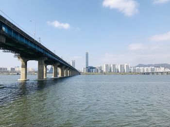 Bridge over river in city against sky