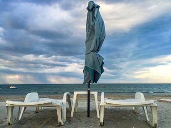 Deck chairs on beach against sky
