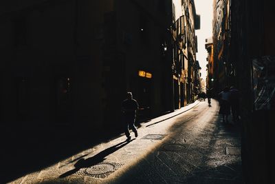 Rear view of man walking on street amidst buildings in city