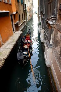 Man in boat amidst buildings on canal