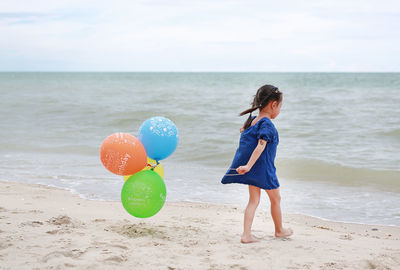 Girl with balloons walking at beach