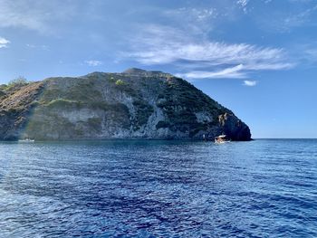 Scenic view of rocks by sea against sky