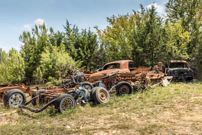 Abandoned car on field against trees