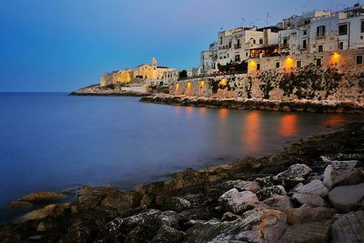 View of town by sea against blue sky at night