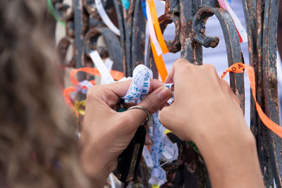 Tourist hands tying souvenir ribbon on the iron railing of the senhor do bonfim church 