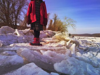 Low section of person standing on snow covered landscape