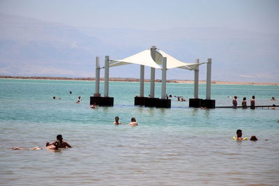 People swimming in sea against sky