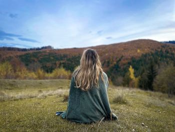 Rear view of woman standing on field against sky