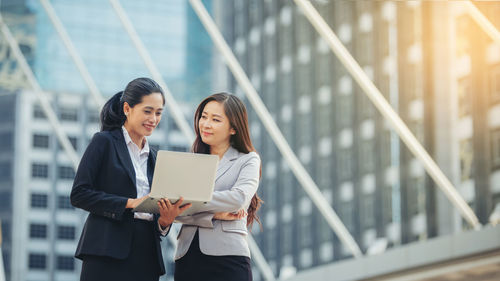 Young businesswoman showing something to colleague on laptop