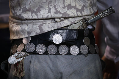 Midsection of man wearing antique belt with knife