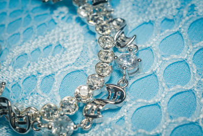 Close-up of necklace on blue textile