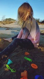 Side profile of 5-year-old girl playing on the beach during late evening. digging in the sand. 