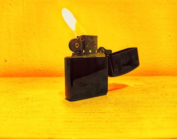 Close-up of electric lamp on table against yellow wall