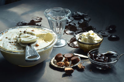 High angle view of ice cream in bowls with peanut butter cupcakes and chocolates on table