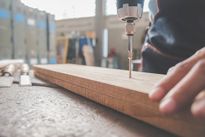 Midsection of woman drilling wood