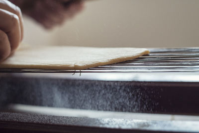 Close-up of very old pasta machine with hand spreading flour on the dough