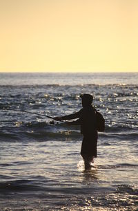 Silhouette man standing on beach against clear sky