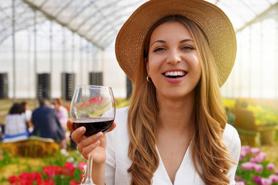 Close-up of young woman looking at camera and holding glass of wine 