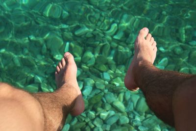 Feet dangling over emerald sea waters.