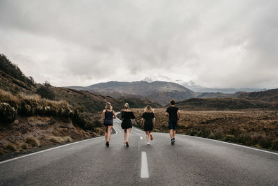 Rear view of people walking on road against sky