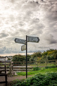 Information sign on field against cloudy sky