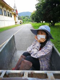 Woman in hat sitting outdoors