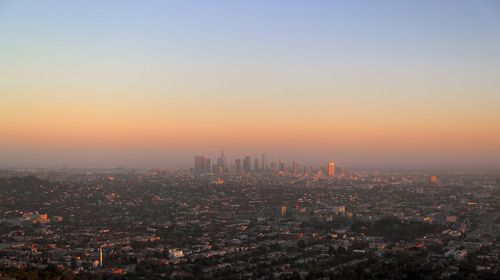 Aerial view of buildings in city against sky during sunset