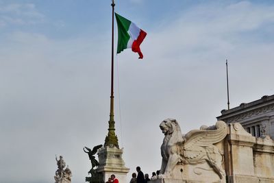 Low angle view of people by italian flag and monument