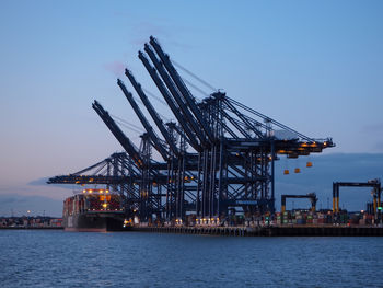 Cranes at commercial dock against sky