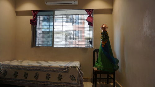 Gudi mounted on chair by single bed near window frame at home during gudi padwa festival 