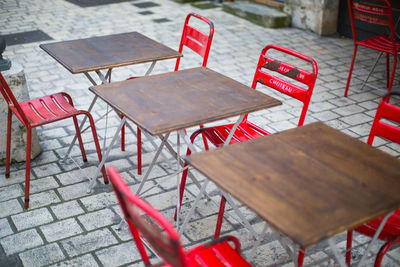 High angle view of empty red chairs by tables at sidewalk cafe