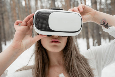 Woman wearing virtual reality simulator against trees outdoors